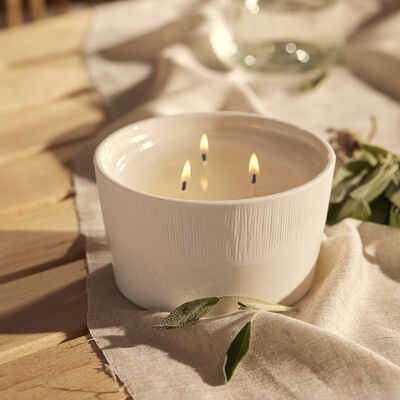 Thymes Sienna Sage 3-Wick Statement Candle Lit on Linen Fabric